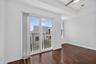 Balcony access with a sliding glass door, wood-finish flooring, a ceiling fan, and a tray ceiling