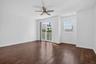 Hardwood-finish flooring, ceiling fan, sliding glass door with balcony access, and a window with blinds