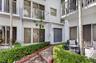 White stucco exterior with a gray double entry door, multiple sliding glass doors, upper-level balconies with white railings, and a tiled walkway