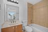 Bathroom featuring a vanity with a light-toned countertop, integrated sink, wood-finish cabinetry, and a full-width mirror