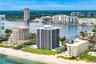 Coastal setting featuring a sandy beach, multiple residential towers, and a prominent waterway with several boats