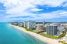 Expansive coastline featuring a sandy beach, multiple high-rise buildings, and a wide waterway with docked boats