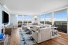 Expansive window wall with balcony access, wood-finish flooring, recessed lighting, and crown molding