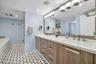 Dual vanity with white countertops, wood-finish cabinetry, and brushed nickel hardware