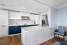 Modern kitchen featuring white and blue cabinetry, a patterned tile backsplash, stainless steel range hood, recessed lighting, and wood-finish floorin