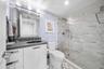Modern bathroom featuring a single vanity with dark countertop, undermount sink, and a framed mirror