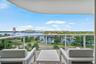 Expansive balcony featuring a glass railing, water frontage, and urban skyline