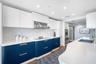 Kitchen featuring white upper cabinetry, blue lower cabinetry, hexagonal patterned backsplash, stainless steel appliances, and an integrated kitchen i