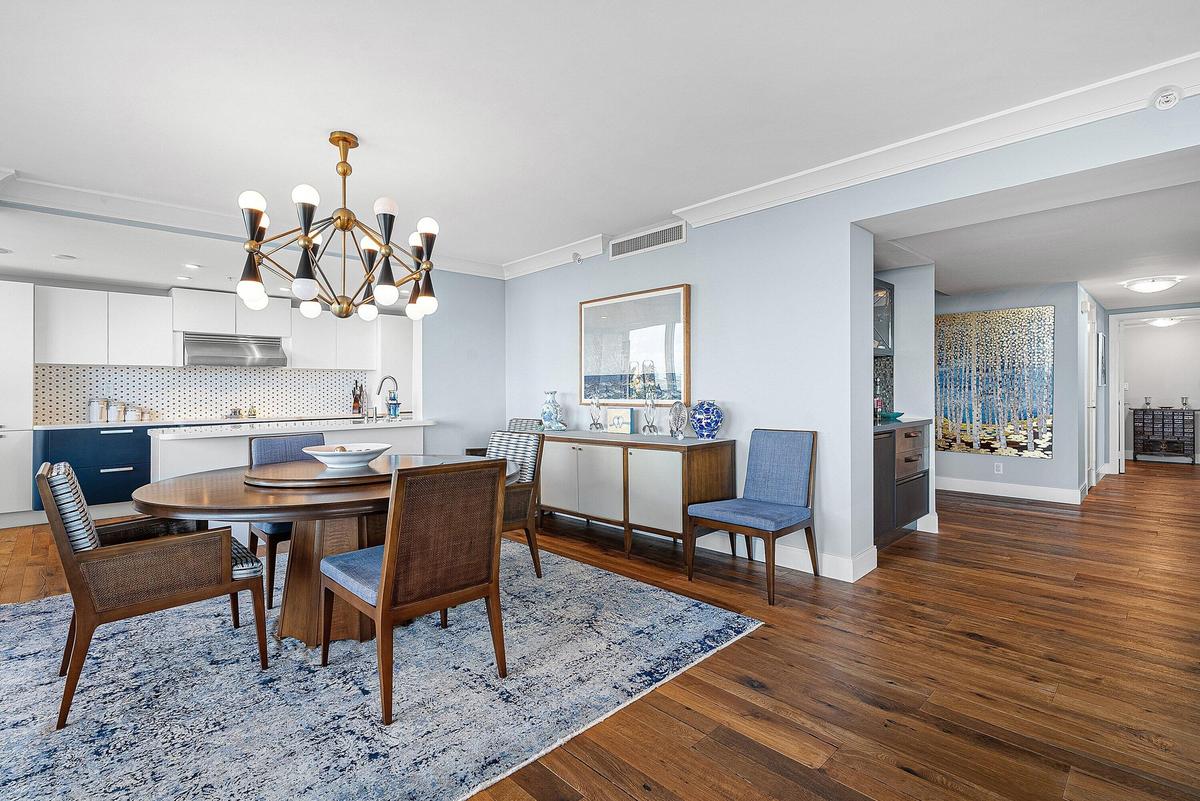 Wood-finish flooring, recessed lighting, crown molding, white cabinetry, and a geometric chandelier