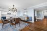 Wood-finish flooring, recessed lighting, crown molding, white cabinetry, and a geometric chandelier