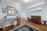 Wood-finish flooring, crown molding, a console table with geometric patterns, and wall sconces