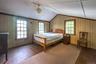 Sloped ceiling with exposed beams, two multi-pane windows, wood-finish wall panels, and wood-finish flooring