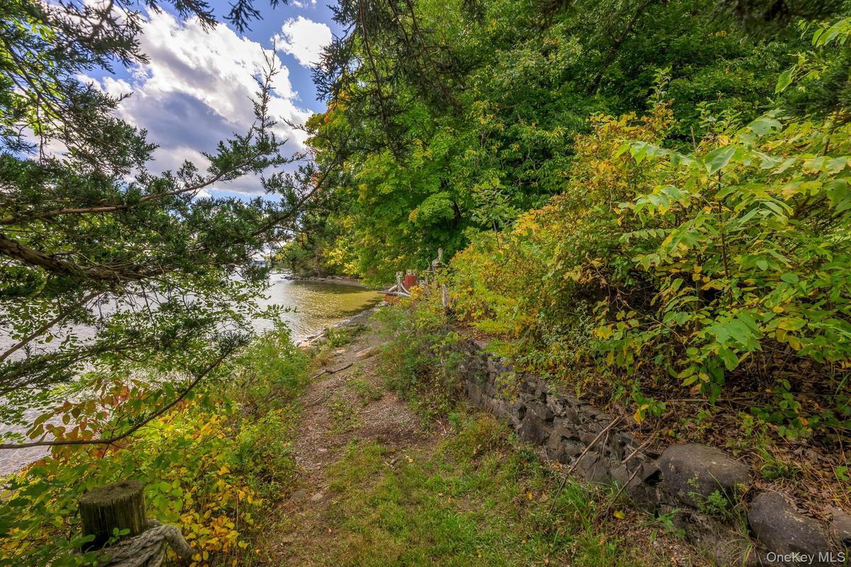 Waterfront property featuring a natural shoreline, lush vegetation, and a stone retaining wall