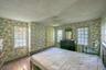 Wood-finish flooring, two large windows, ceiling fan with light fixture, and a solid interior door