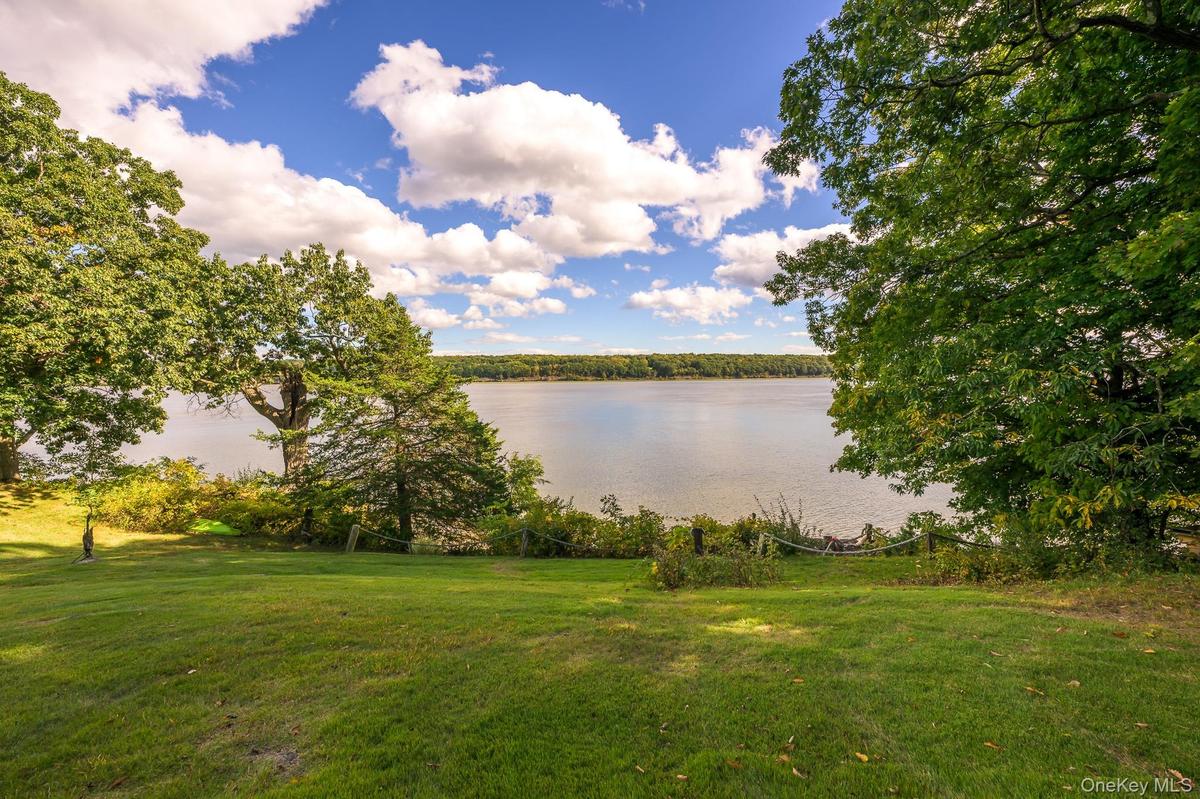 Expansive lawn area with mature trees and waterfront scenery