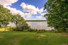 Expansive lawn area with mature trees and waterfront scenery