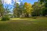 Expansive green lawn with mature trees and a distant body of water