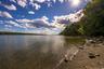 Shoreline property featuring a natural pebble beach and mature trees bordering the water