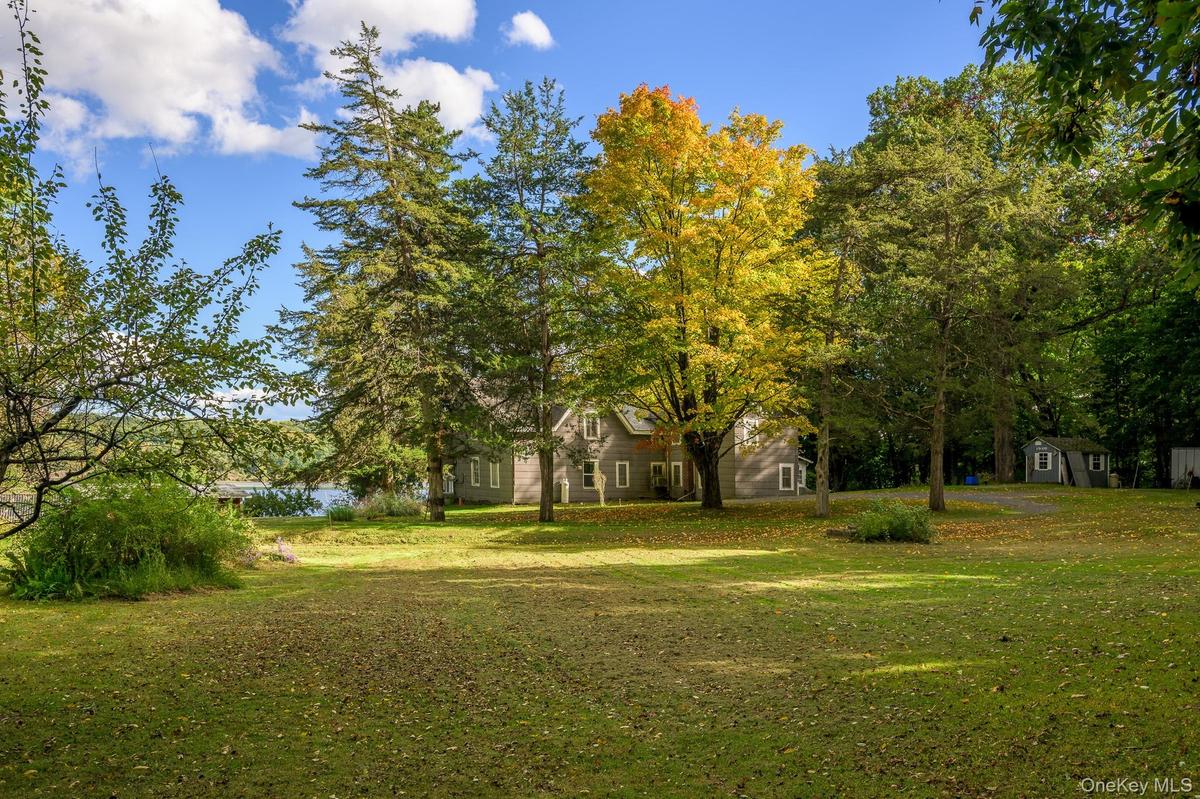 Expansive lawn area with mature trees and a visible body of water
