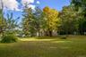 Expansive lawn area with mature trees and a visible body of water
