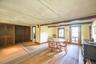 Hardwood flooring throughout, exposed ceiling beams, built-in wooden cabinetry, single-pane window with wooden frame, and a glass-paneled exterior doo