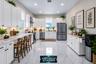 Kitchen with white cabinetry, stainless appliances and breakfast bar (virtually staged)