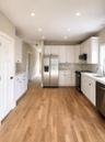 Open-concept kitchen featuring wood-finish flooring, white cabinetry, stainless steel appliances, white countertops, and recessed lighting