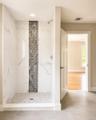 Walk-in shower with white marbled tile walls, a vertical accent strip of rectangular mosaic tiles, and a mosaic tile floor