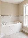 Soaking tub with chrome fixtures, surrounded by white marble-look tile