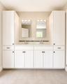 Double vanity with white cabinetry and dark hardware