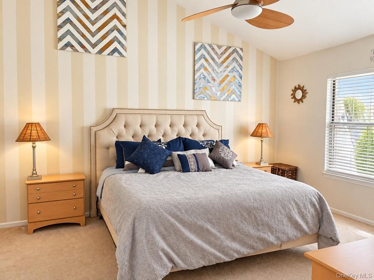 Vaulted ceiling featuring a ceiling fan, window with blinds, and striped wall covering