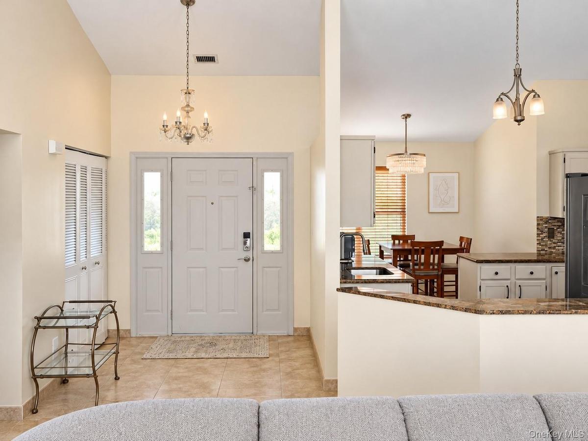 Vaulted entry with decorative chandelier, tile flooring, and double-pane sidelight windows