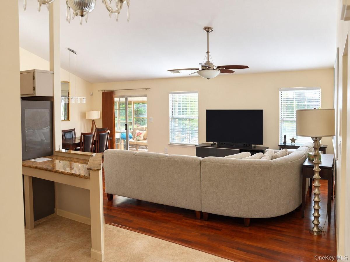Hardwood-finish flooring, recessed lighting, ceiling fan, sliding glass door, and granite-finish countertop on a built-in desk