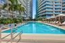 Swimming pool featuring a tiled perimeter, stainless steel entry rails, integrated landscaping, and paved poolside decking