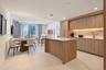 Modern kitchen featuring wood-finish cabinetry, a central island with a stone-surface countertop, integrated appliances, under-cabinet lighting, and s