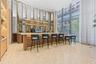 Custom bar featuring a stone countertop, tiered shelving with integrated lighting, a fluted wood-finish front panel, mirrored backsplash, and floor-to