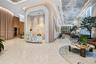 Open lobby featuring terrazzo flooring, fluted wood paneling, arched architectural detailing, a stone-cladding reception desk, and a decorative coffer