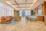 Coffered ceiling with recessed lighting, full-height windows, wood-finish geometric flooring, and custom built-in bar with stone-surfaced counter and 