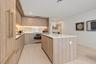 Kitchen featuring wood-finish cabinetry, a large central island with a quartz countertop, integrated under-cabinet lighting, and a stone-style backspl