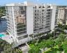 Multi-story residential building featuring floor-to-ceiling glass paneling, tiered cantilevered balconies with glass railings, an attached swimming po