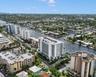 Aerial perspective of a high-rise residential structure positioned along a deep-water canal, featuring expansive balconies, concrete building construc