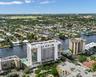 High-rise building featuring extensive glass facade, private balconies, a ground-level swimming pool, and direct waterfront positioning