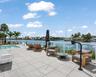 Waterfront terrace featuring a tiled deck, built-in pool, and glass railing system overlooking the canal