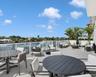 Expansive terrace featuring large-format tile flooring, a glass-panel railing system, and direct waterfront exposure