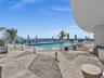 Experience oceanfront resort-style living at Apogee Beach, featuring an inviting swimming pool, expansive pool deck, sleek glass railings, and direct 