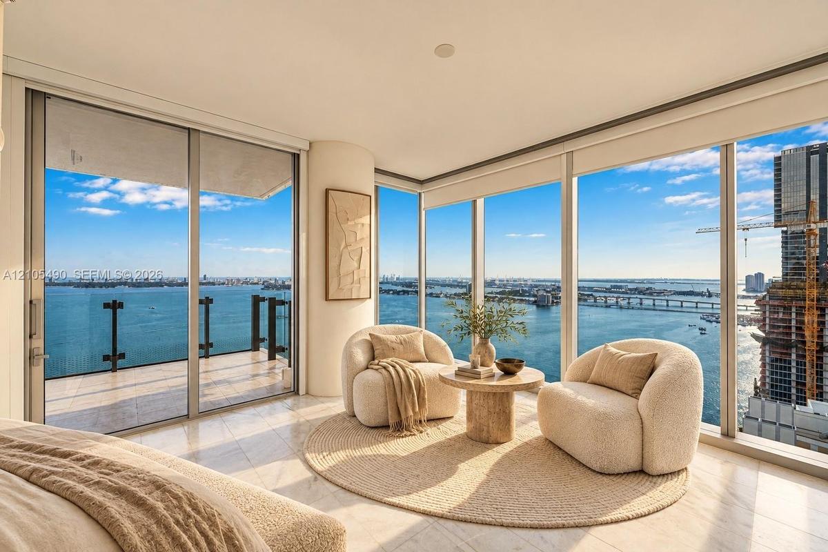 Floor-to-ceiling windows, wrap-around balcony with glass railing, stone-finish flooring, and expansive water scenery