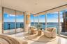 Floor-to-ceiling windows, wrap-around balcony with glass railing, stone-finish flooring, and expansive water scenery