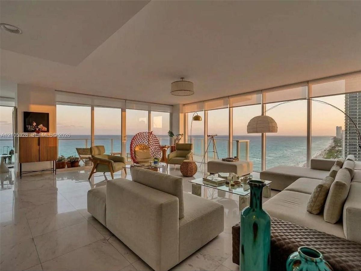 Expansive living area featuring floor-to-ceiling windows, panoramic ocean views, polished marble flooring, and recessed ceiling lighting.