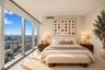 Floor-to-ceiling windows, neutral interior wall palette, stone-finish flooring, and expansive urban skyscape
