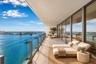 Expansive terrace featuring large-format stone flooring, a transparent glass panel railing, and full-height sliding glass doors